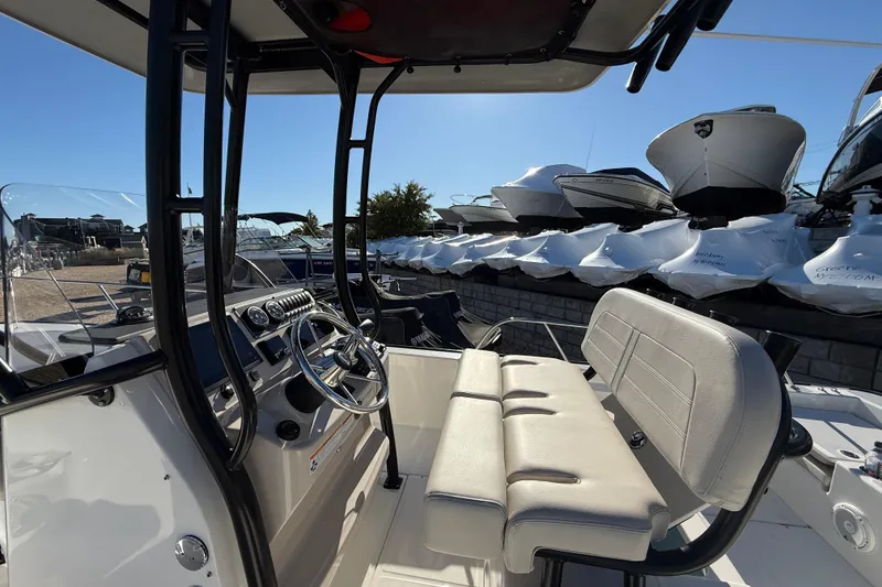 Slide: The Image of 2023 Boston Whaler 210 Montauk boat interior with steering wheel and seating, docked outdoors. - 11