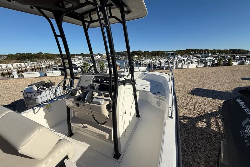 Slide: The Image of 2023 Boston Whaler 210 Montauk boat at marina, featuring modern console and seating. - 12