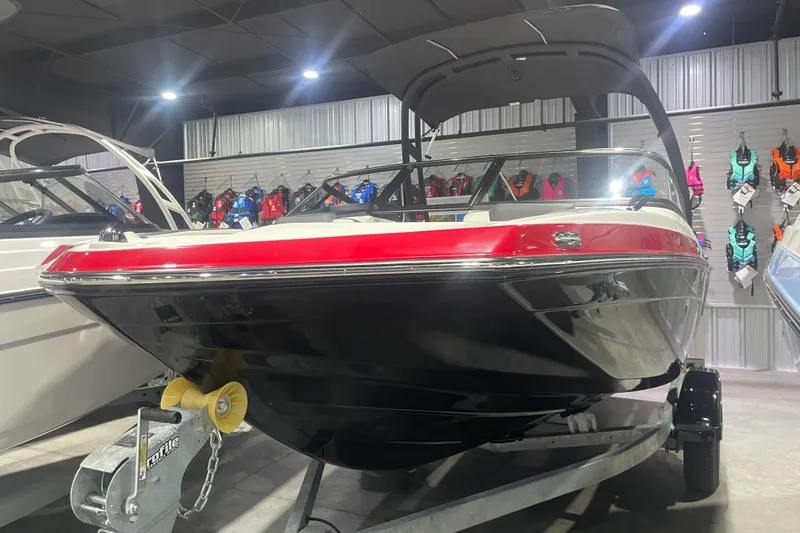 Slide: The Image of 2025 Yamaha Boats AR195 in showroom, red and black design, displayed with life jackets. - 0