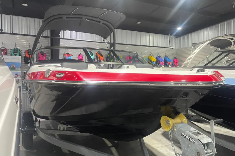 Slide: The Image of 2025 Yamaha Boats AR195 in showroom, red and black design, displayed with life jackets. - 1