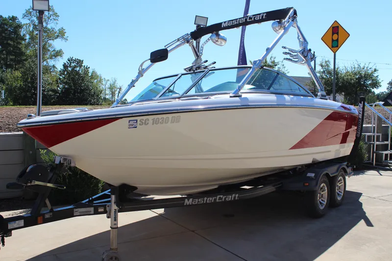 Slide: The Image of 2011 MasterCraft X-15 boat on trailer, red and white design, parked outdoors. - 6