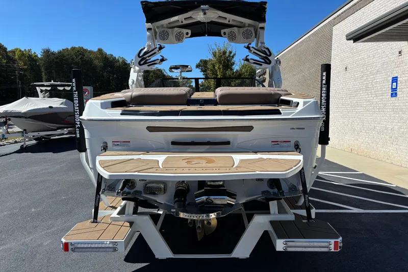 Slide: The Image of 2026 Centurion Ri230 boat on trailer, parked outdoors, surrounded by trees. - 6