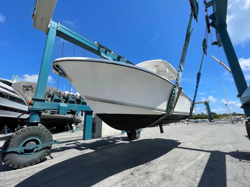 Slide: The Image of 2015 Pursuit S 280 Sport boat lifted by crane under clear blue sky. - 4