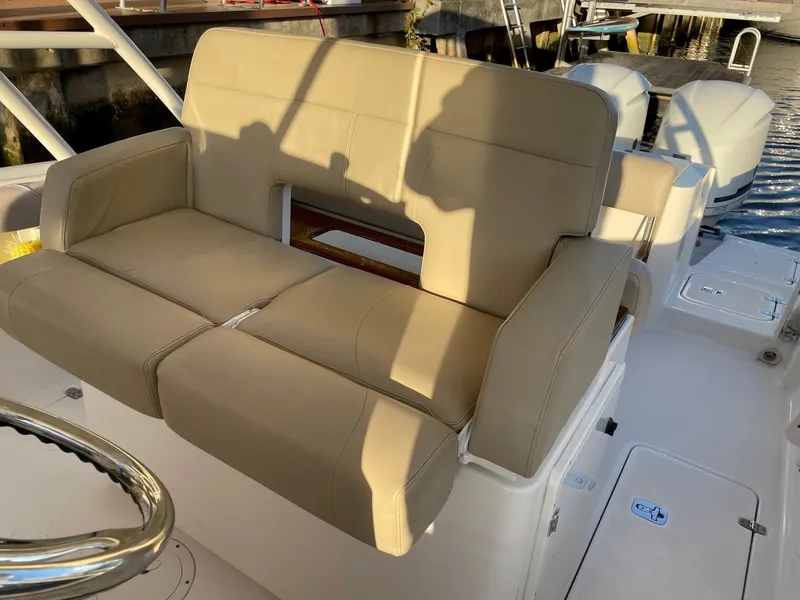 Slide: The Image of 2015 Pursuit S 280 Sport boat with beige cushioned seating, docked by the water. - 6