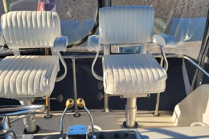 Slide: The Image of Captain's chairs on 1988 Tiara Yachts 3600 Convertible, featuring white upholstery and control levers. - 20