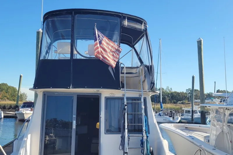 Slide: The Image of 1988 Tiara Yachts 3600 Convertible docked, featuring flybridge and American flag. - 4