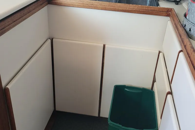 Slide: The Image of 1988 Tiara Yachts 3600 Convertible kitchen corner with white cabinets and green trash bin. - 51