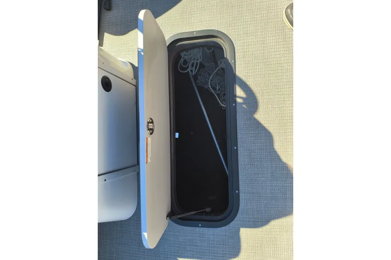 Slide: The Image of Open storage compartment on 2022 Manitou Aurora VP 23 boat, showing interior space. - 15