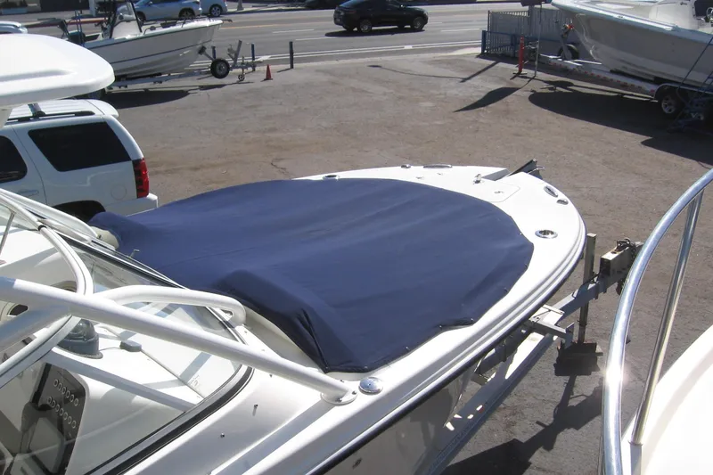 Slide: The Image of 2024 Edgewater 248CX Crossover boat with blue cover in a parking lot. - 16