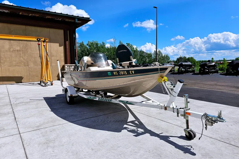 Slide: The Image of 2000 Alumacraft Navigator 165 CS boat on trailer, parked outdoors under blue sky. - 2