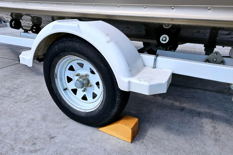 Slide: The Image of Trailer wheel of 2000 Alumacraft Navigator 165 CS secured with a yellow chock. - 25
