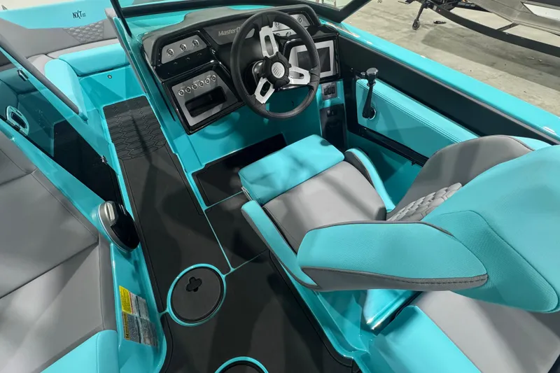 Slide: The Image of 2026 MasterCraft NXT22 boat interior with turquoise and gray seating, modern dashboard, and steering wheel. - 14