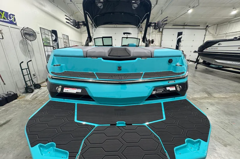 Slide: The Image of 2026 MasterCraft NXT22 boat in a showroom, featuring a vibrant turquoise exterior. - 3