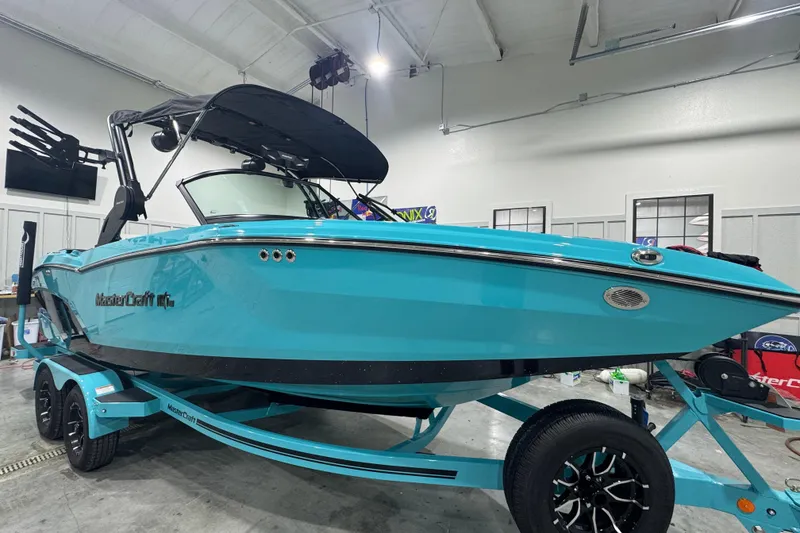 Slide: The Image of 2026 MasterCraft NXT22 boat in a showroom, featuring a sleek turquoise design. - 4