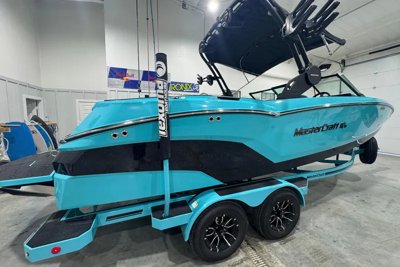 Slide: The Image of 2026 MasterCraft NXT22 boat in a showroom, vibrant blue and black design. - 5
