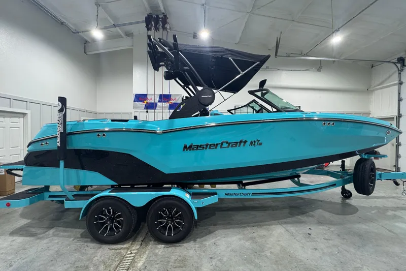 Slide: The Image of 2026 MasterCraft NXT22 boat in a garage, vibrant blue color, on a matching trailer. - 6