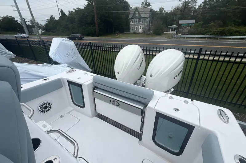 Slide: The Image of 2026 Sportsman Open 262 Center Console boat with twin Yamaha engines, parked near a fence. - 7