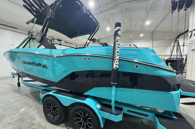 Slide: The Image of 2026 MasterCraft NXT22 boat in a showroom, vibrant turquoise color, on a matching trailer. - 15