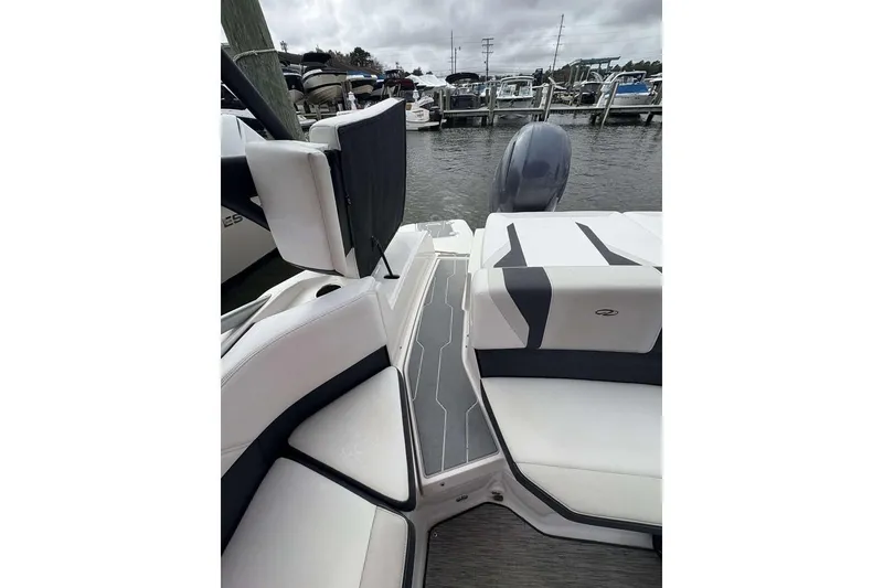 Slide: The Image of 2018 Regal 21 OBX boat interior with sleek seating and modern design at a marina. - 17