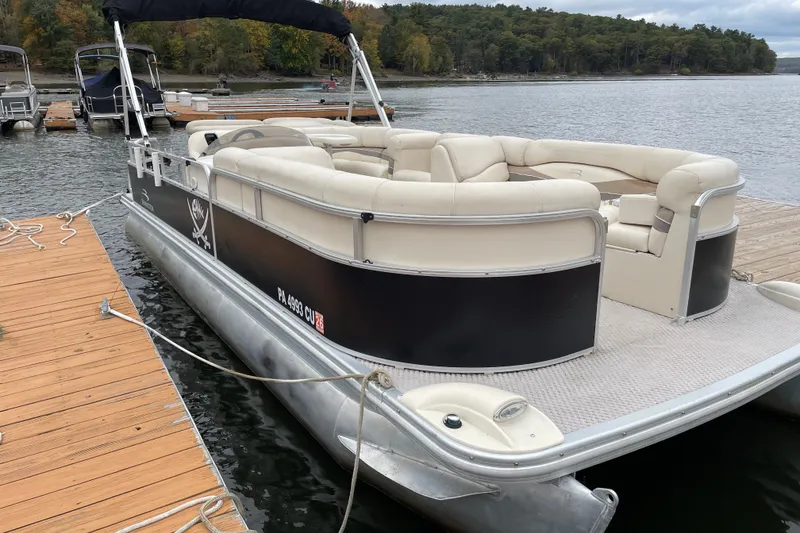 The Image of 2005 Bennington 2275RL pontoon boat docked on a lake with lush forest background. - 0
