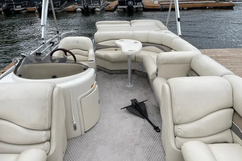 Slide: The Image of 2005 Bennington 2275RL pontoon boat with spacious seating and helm, docked by the water. - 10