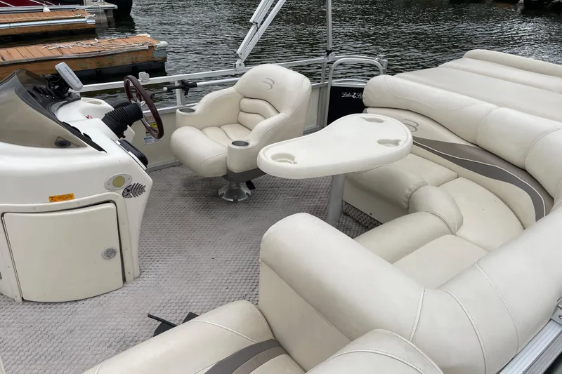 Slide: The Image of 2005 Bennington 2275RL pontoon boat interior with plush seating and steering console. - 4