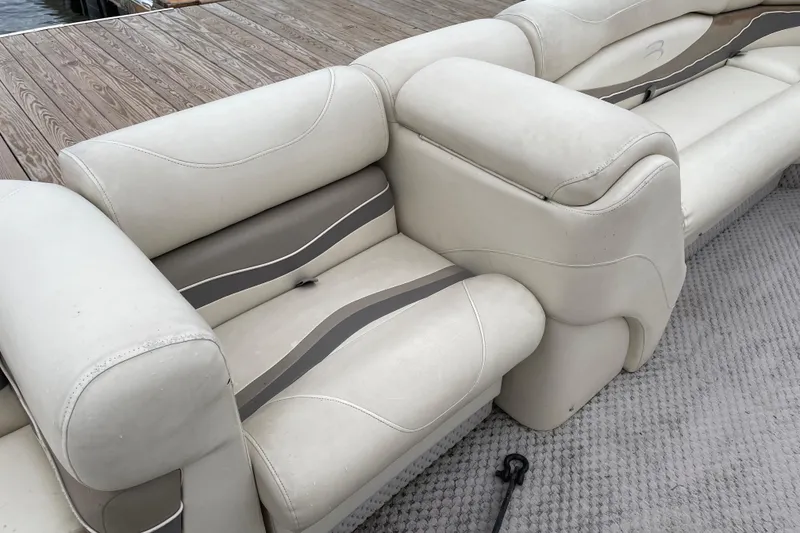 Slide: The Image of 2005 Bennington 2275RL boat interior with beige and gray seating near dock. - 9