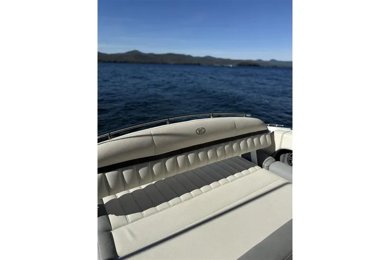 Slide: The Image of 2017 Cobalt 24SD boat with beige seating, overlooking a serene lake and distant hills. - 16