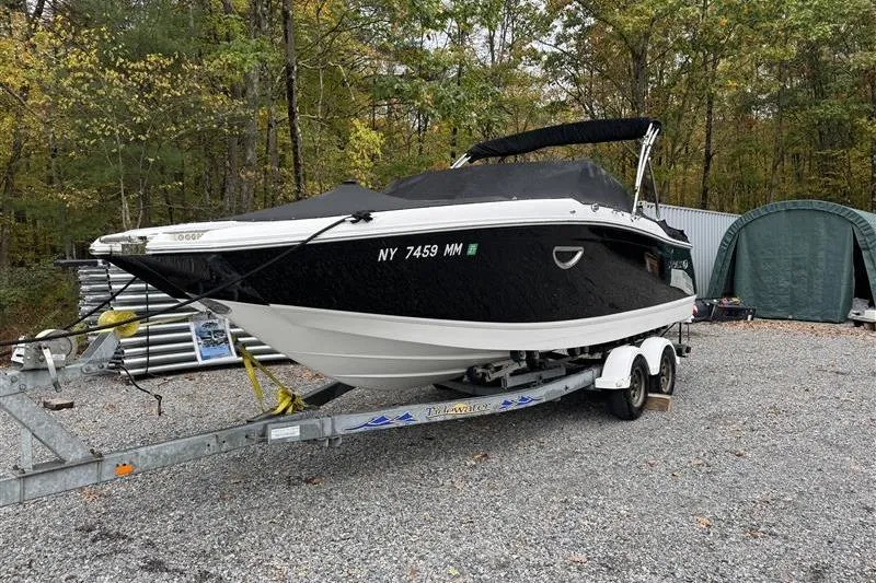 Slide: The Image of 2017 Cobalt 24SD boat on trailer, parked outdoors with forest background. - 2