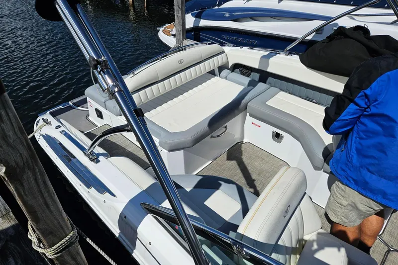 Slide: The Image of 2017 Cobalt 24SD boat interior with white seating and chrome details at a dock. - 20