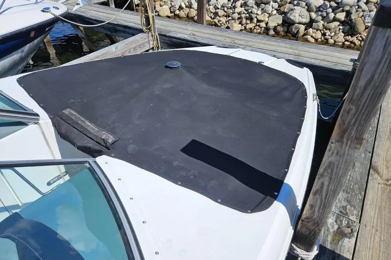 Slide: The Image of 2017 Cobalt 24SD boat with black cover docked by wooden pier. - 24