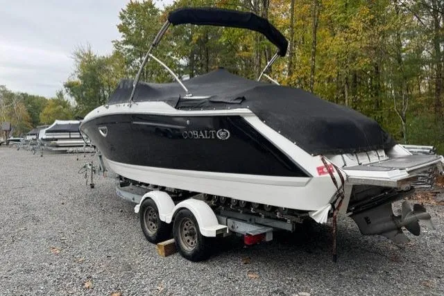 Slide: The Image of 2017 Cobalt 24SD boat on trailer, covered, parked outdoors near trees. - 32