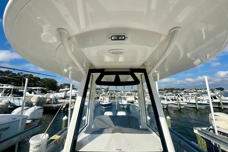 Slide: The Image of 2025 Regulator 23 boat docked at marina, surrounded by other vessels under a clear sky. - 17
