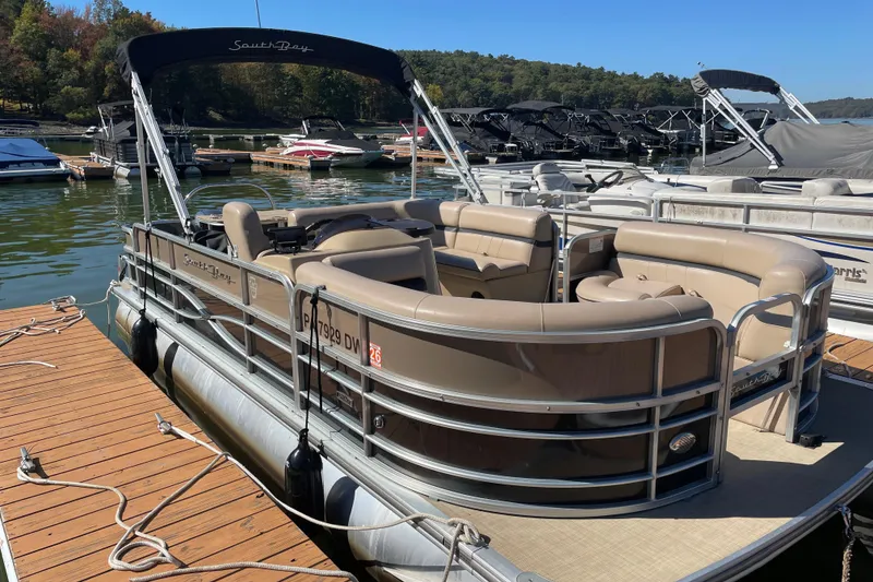 The Image of 2018 South Bay 222FLR pontoon boat docked at a marina with scenic background. - 1