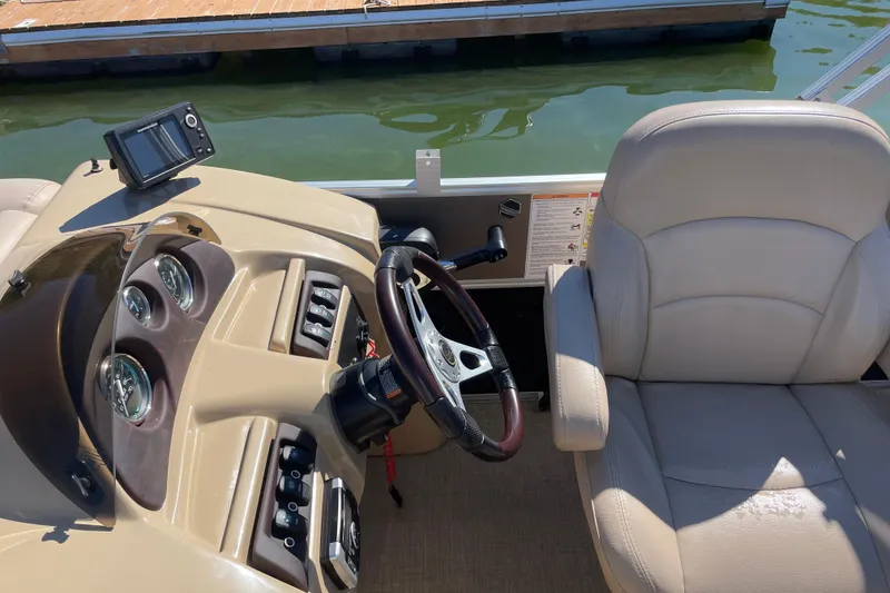 Slide: The Image of Captain's seat and dashboard of 2018 South Bay 222flr boat, docked by water. - 5