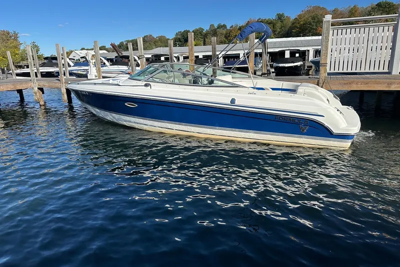 Slide: The Image of 2003 Formula 260 Sun Sport boat docked on a sunny day, blue and white design. - 2