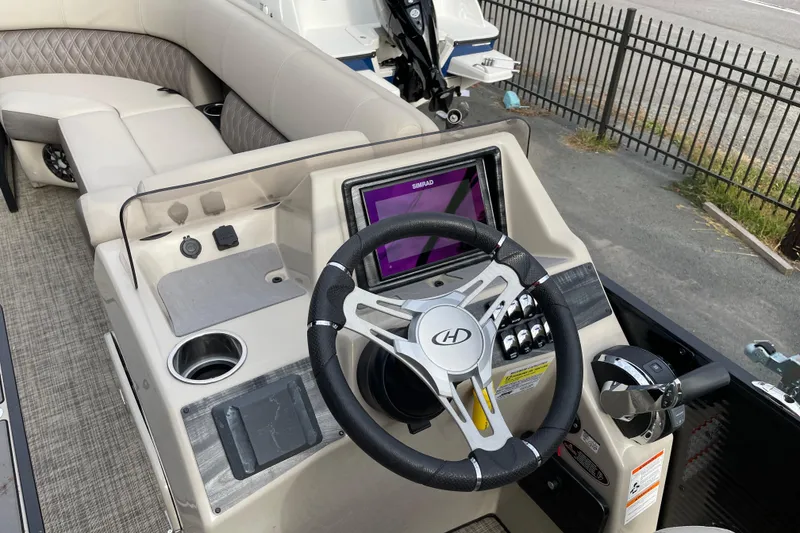 Slide: The Image of 2021 Harris Sunliner 230 boat dashboard with steering wheel and navigation display. - 5