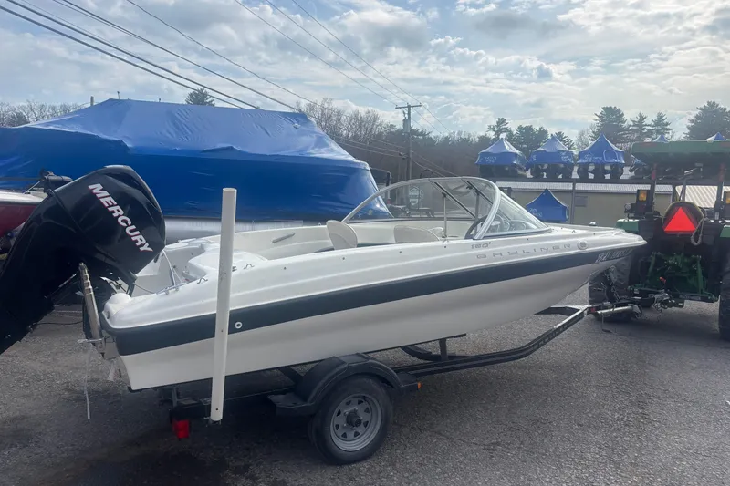 Slide: The Image of 2011 Bayliner 160 Bowrider boat on trailer with Mercury outboard motor, parked outdoors. - 10
