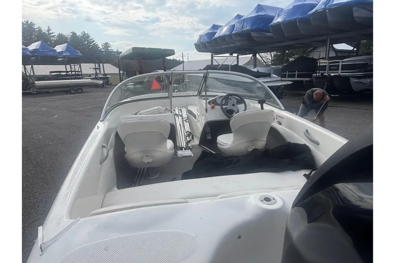 Slide: The Image of 2011 Bayliner 160 Bowrider boat interior with steering wheel and seating, parked outdoors. - 14