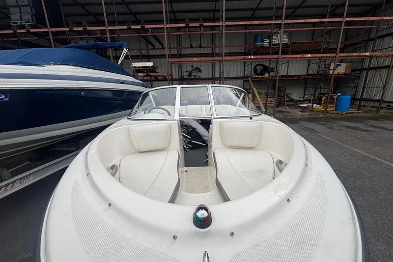 Slide: The Image of 2011 Bayliner 160 Bowrider boat in storage, featuring white seating and windshield. - 4