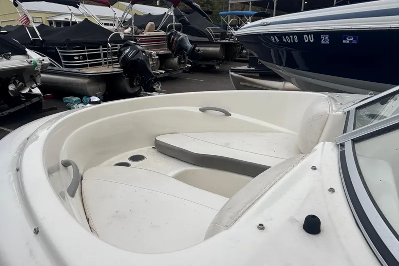 Slide: The Image of 2011 Bayliner 160 Bowrider boat interior with seating and cup holders, docked among other boats. - 5