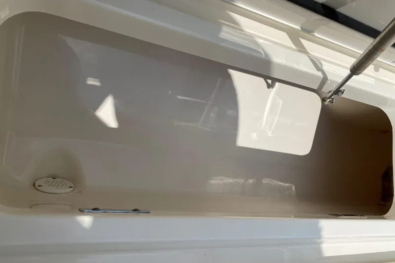 Slide: The Image of 2017 Boston Whaler 320 Vantage storage compartment, open and empty, with sunlight casting shadows. - 44