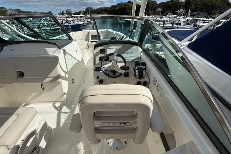 Slide: The Image of 2015 Boston Whaler 270 Vantage boat interior with steering wheel and controls, docked at marina. - 12