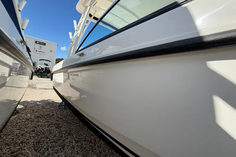 Slide: The Image of 2015 Boston Whaler 270 Vantage boat in a marina, side view under clear blue sky. - 25