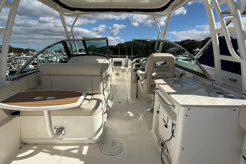 Slide: The Image of 2015 Boston Whaler 270 Vantage interior with seating, table, and helm under a clear sky. - 6