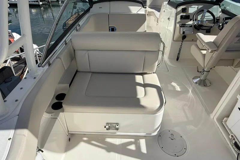 Slide: The Image of 2015 Boston Whaler 270 Vantage interior with seating and helm, docked at marina. - 9
