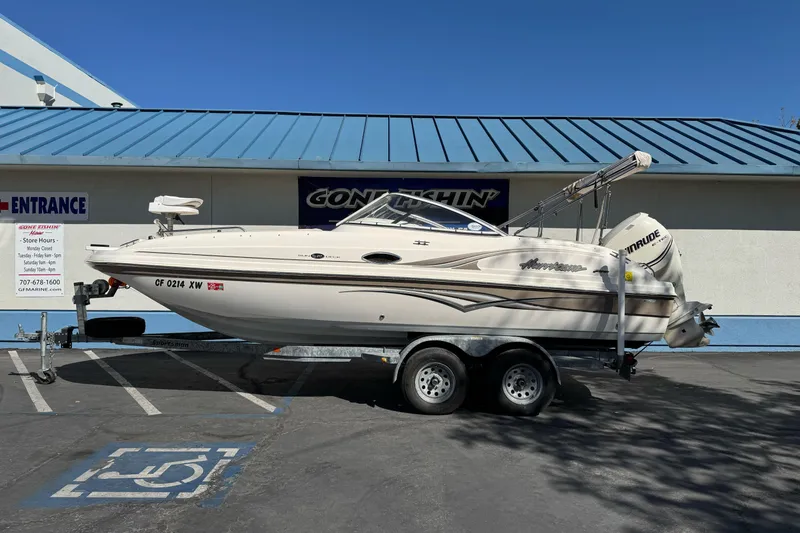 Slide: The Image of 2007 Hurricane SunDeck 217 OB boat on trailer, parked outside a building. - 0