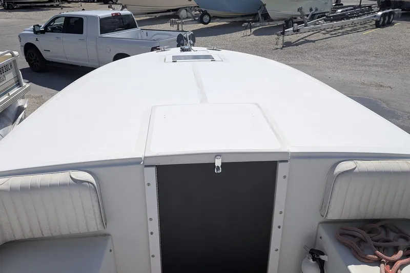 Slide: The Image of 1989 Intrepid 29 boat deck with white seating, parked near a white truck. - 5