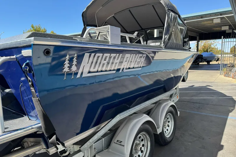 Slide: The Image of 2023 North River 21 X 84 Seahawk boat on trailer, blue exterior, parked outdoors. - 9