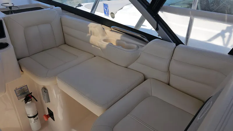 Slide: The Image of 2016 Grady-White Express 330 interior seating with beige upholstery and window view. - 26